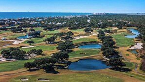 Een golfbaan met verschillende vijvers en een woonwijk op de achtergrond.