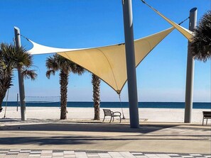 Eine Uferpromenade mit Palmen, einer Bank und Blick aufs Meer.