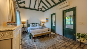A bedroom with a bed, bench, dresser, bedside tables, and a green door. - ELIVAAS Villa Seine 3-BHK villa (Pilerne Industrial Estates)