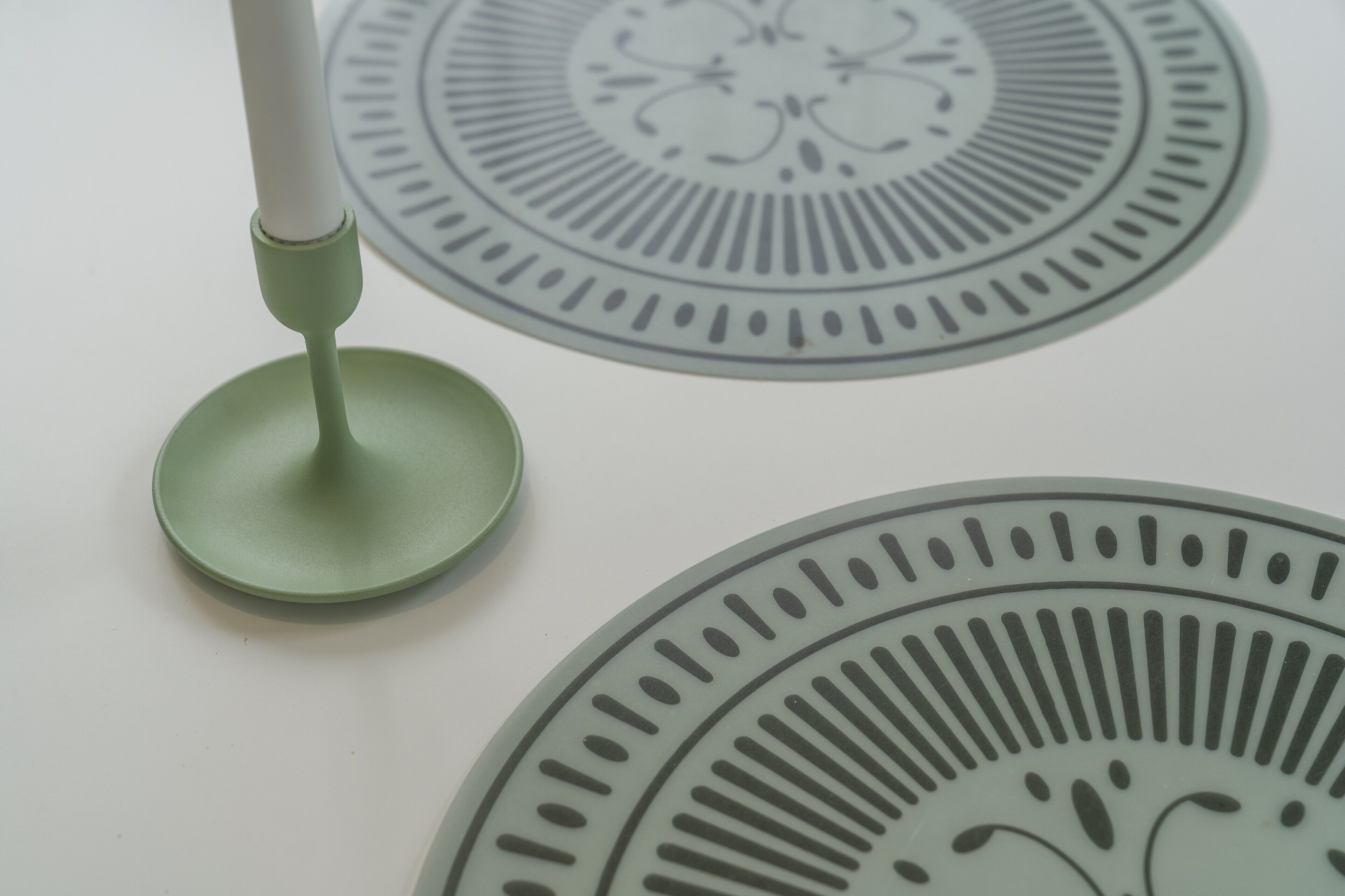 Un gros plan d’une table verte avec un pied blanc, peut-être une lampe de table, et un tapis au motif décoratif.