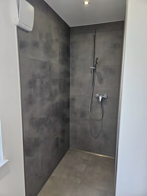 Ducha moderna con cabezal de ducha de mano y grifo empotrado.