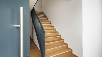 A wooden staircase with a metal handrail and a blue door on the left.