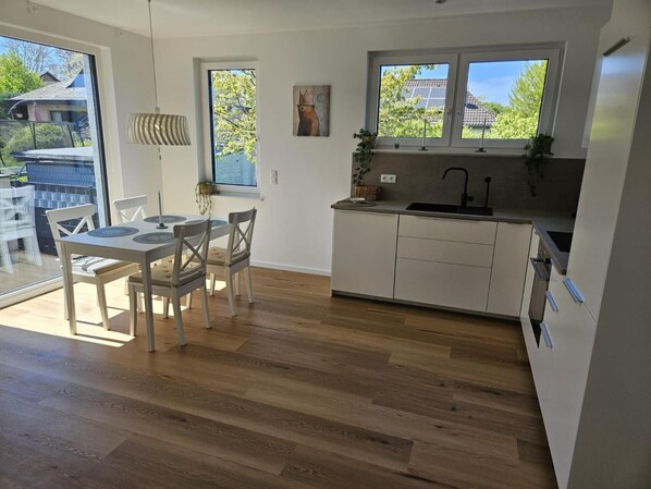 Eine moderne Küche mit Essbereich, großen Fenstern und Blick ins Freie.