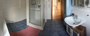 Une salle de bain avec une douche, un lavabo et un miroir.
