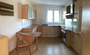 Une cuisine avec des meubles de rangement en bois, un four encastré et une fenêtre.