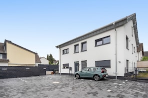 A modern two-story building with a car parked in front. - Sophia Apartment in New Building with Balcony (Grafschaft)