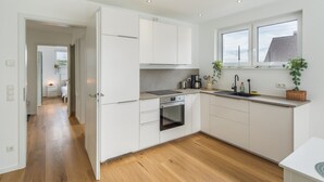 Una cocina moderna con armarios blancos, horno integrado y ventana sobre el fregadero.