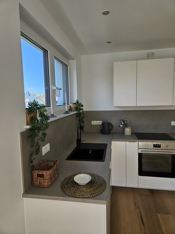 A modern kitchen with a built-in sink, a stove, and a window with a view of the outside.