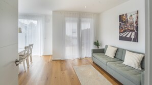 Una sala de estar moderna con un sofá gris, un tapete blanco y una pintura de un paisaje urbano en la pared.