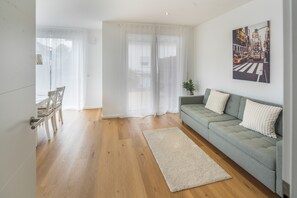 Un salon moderne avec un canapé gris, un tapis blanc et un tableau représentant un paysage urbain accroché au mur.