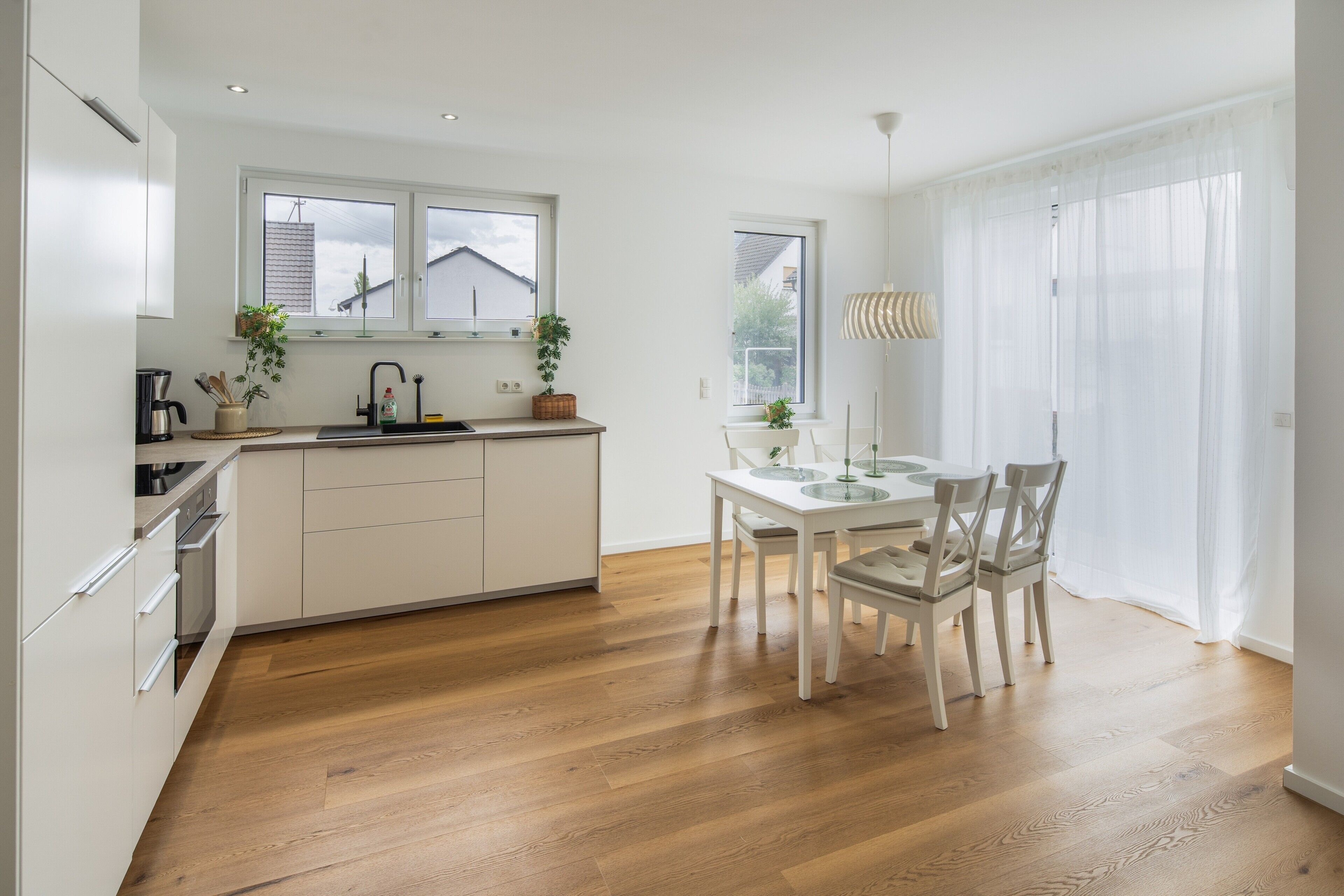 Eine moderne Küche mit Essbereich, Holzboden und großen Fenstern.