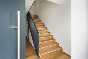 A wooden staircase with a metal handrail and a blue door on the left.