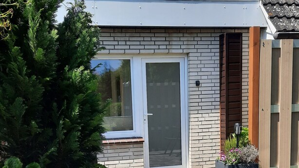 A modern house with a brick exterior, a large window, and a door. - Vacation Apartment on the Weser River (Elsfleth)