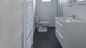 A modern bathroom with a toilet, sink, and radiator. - Holiday Home in Halfweg With Terrace (Halfweg)