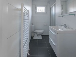 A modern bathroom with a toilet, sink, and radiator. - Holiday Home in Halfweg With Terrace (Halfweg)