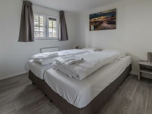 A bedroom with a bed, a window with curtains, a radiator, a nightstand, and a painting on the wall. - Holiday Home in Halfweg With Terrace (Halfweg)