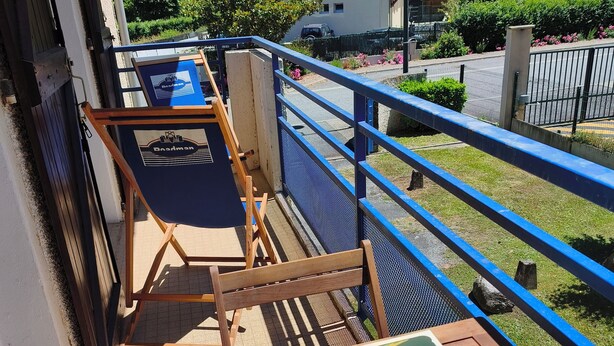A balcony with a wooden table, two lounge chairs, and a poster. - Les Hauts de Saint Mamet: On the Road to Spain! (Saint-Mamet)