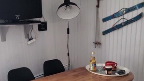 A wooden dining table with chairs, a television, a lamp, skis, and a bottle of olive oil on the table. - Les Hauts de Saint Mamet: On the Road to Spain! (Saint-Mamet)