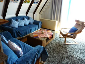 A room with a blue sofa, a wooden armchair, and a small table with a placemat.
