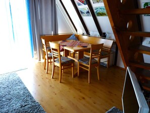 A dining area with a wooden table and chairs, a rug, and a staircase.