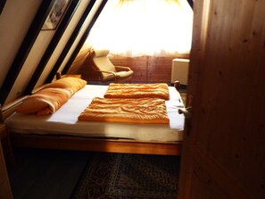 A small, cozy room with a single bed, a chair, and a window.