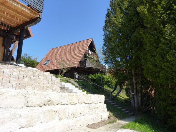 A house with a sloped roof, a stone staircase, and a wooden deck.