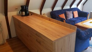Ein gemütlicher Wohnraum mit einem Holzkasten, einer Couch und einem kleinen Tisch.