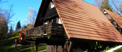 Une maison en bois avec un toit en pente, un balcon et un petit porche.