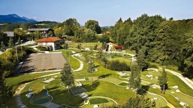 A landscaped area with pathways, trees, and a building with a red roof. - Vacation Home at Weidenstraße 3 (Siegsdorf)