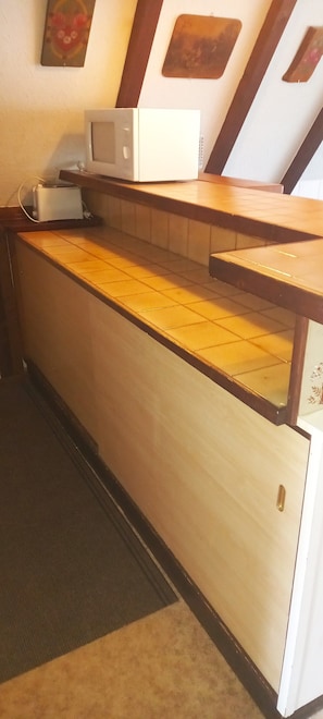 Una cocina equipada con microondas, tostadora y encimera de baldosas.