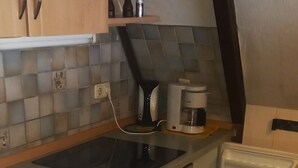 A compact kitchen with wooden cabinets, a built-in oven, a coffee maker, and a small sink. - Vacation Home at Weidenstraße 3 (Siegsdorf)