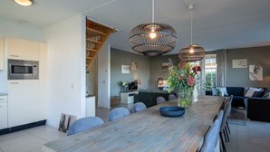 Eine moderne Küche mit integriertem Mikrowellenherd, ein Essbereich mit Holztisch und -stühlen sowie ein Wohnzimmer mit Sofa und Couchtisch.