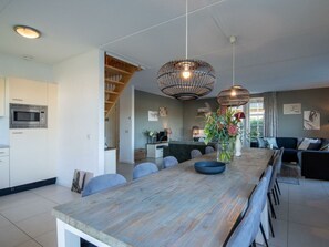 A modern kitchen with a built-in microwave, a dining area with a wooden table and chairs, and a living room with a sofa and a coffee table. - Daelenbroeck 12 (Susteren)