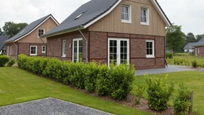 Ein modernes, zweistöckiges Haus mit Satteldach, großen Fenstern und einem gepflegten Rasen.