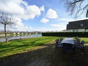 A patio with a table and chairs, a pond, and a building with a tiled roof. - Daelenbroeck 12 (Susteren)