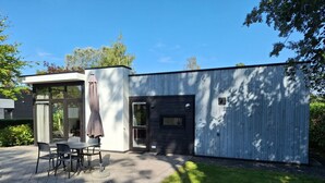 Moderni rakennus, jossa on patio, ruokapöytä ja tuoleja.
