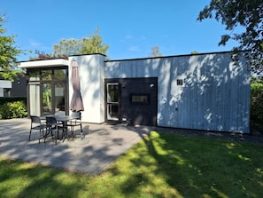 Ein modernes Gebäude mit einer Terrasse, einem Esstisch und Stühlen.