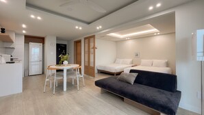 Um espaço compacto com cozinha americana, área de jantar com mesa e cadeiras, sofá e duas camas.