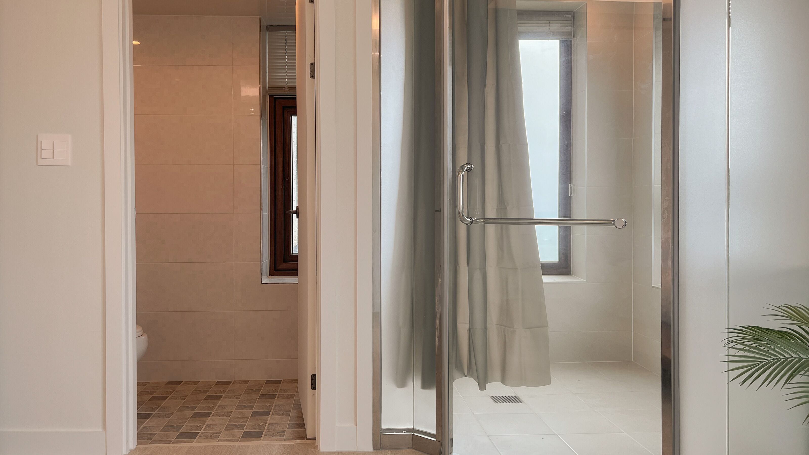 A bathroom with a glass shower door, a toilet, and a window.