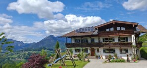 Eine zweistöckige Chalet mit Balkon, Solaranlage und Bergblick.