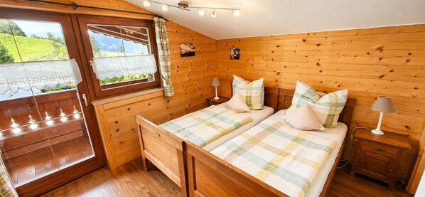 Ein Schlafzimmer mit Holzwandverkleidung, einem Bett, Nachttischen und einem Fenster mit Vorhängen.