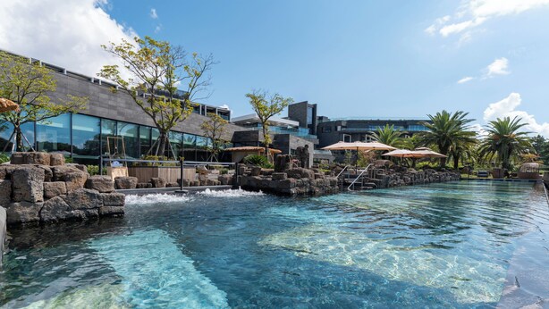 A clear pool with a waterfall feature, modern architecture, and outdoor seating areas. - O'REVE Resort (Seogwipo)
