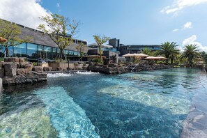 Una piscina cristalina con cascada, arquitectura moderna y zonas de estar al aire libre.