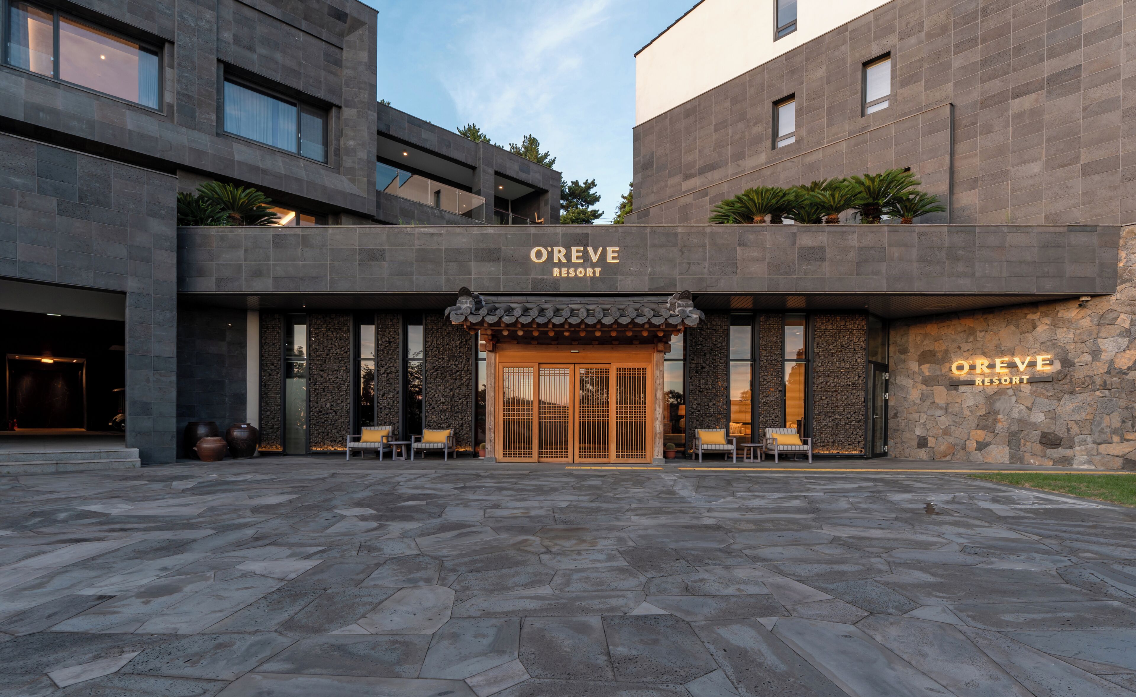 A modern building with a stone facade, a sign reading 'O'REVE RESORT,' and a traditional entrance with a tiled roof.