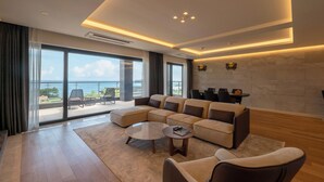 A modern living room with a sectional sofa, a coffee table, and a view of the outdoors. - O'REVE Resort (Seogwipo)