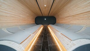 A sauna with wooden walls and benches, a tiled floor, and a ceiling light. - O'REVE Resort (Seogwipo)
