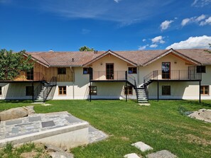 Un bâtiment à deux étages, doté d’un toit recouvert de tuiles, de plusieurs balcons et d’une cour verdoyante.
