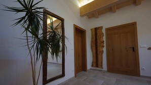 Passadís amb una planta en test, portes de fusta i un mirall gran.