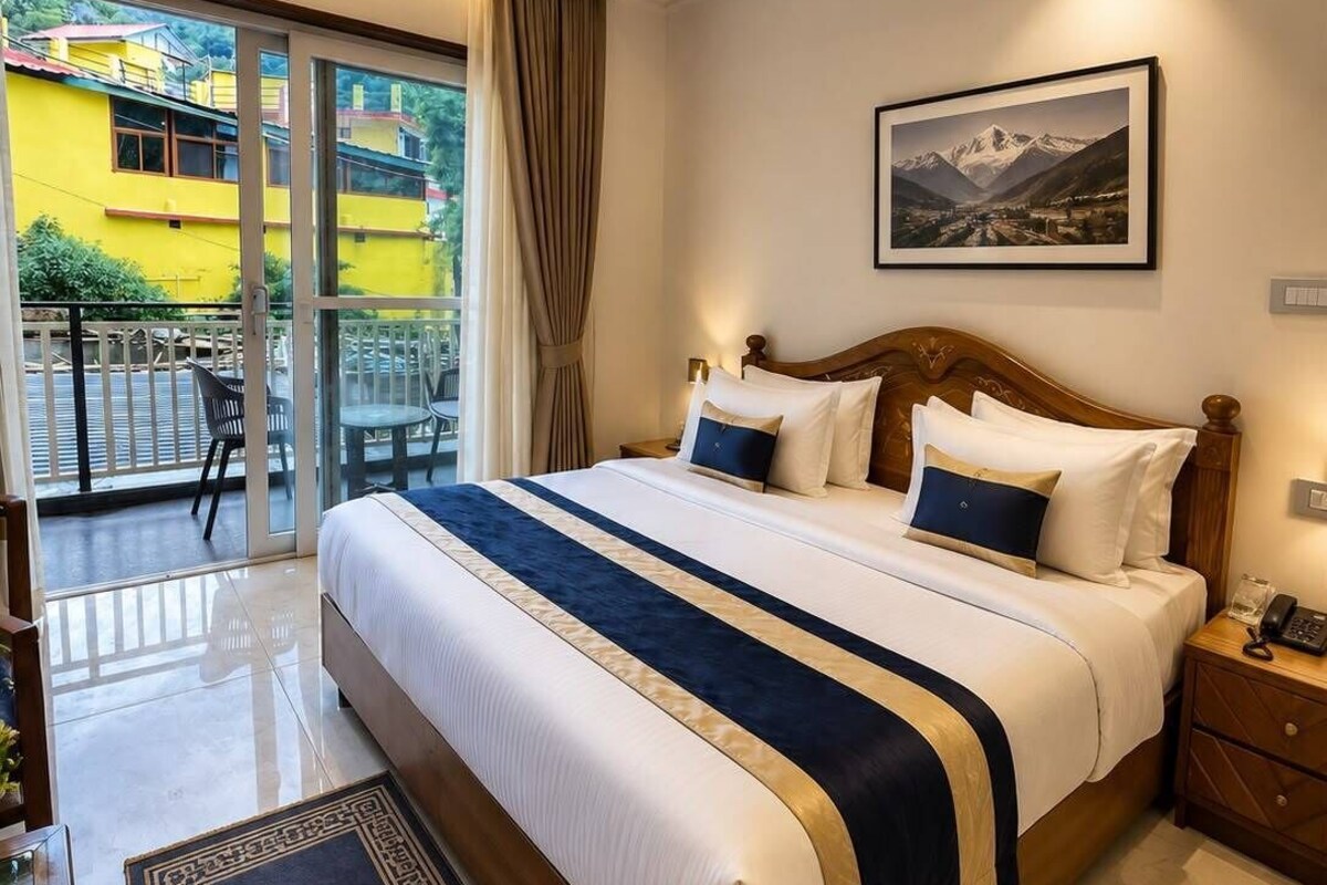 A hotel room with a large bed, a view of the outside, a painting on the wall, and a nightstand with a phone.