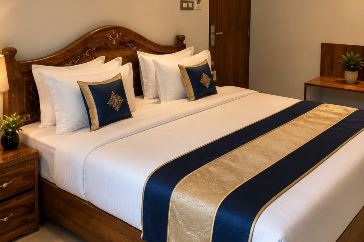 A neatly made bed with a wooden headboard, white bedding, and decorative pillows.